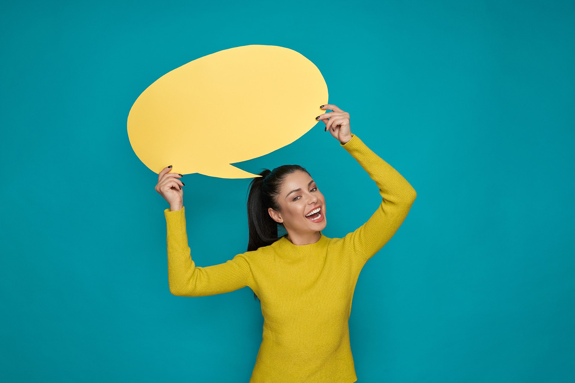 Happy girl holding yellow paper speech bubble over head